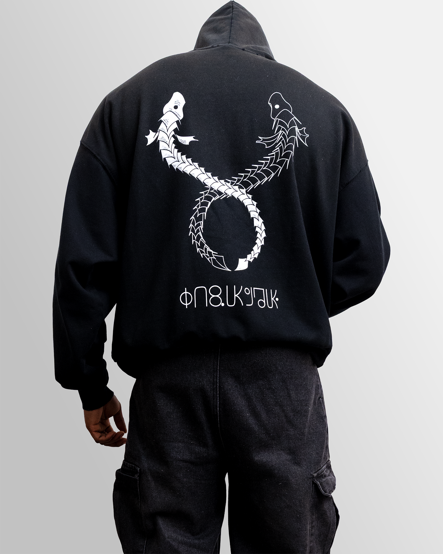 Black hoodie with a white dragon design on the back, worn by a person against a gray background