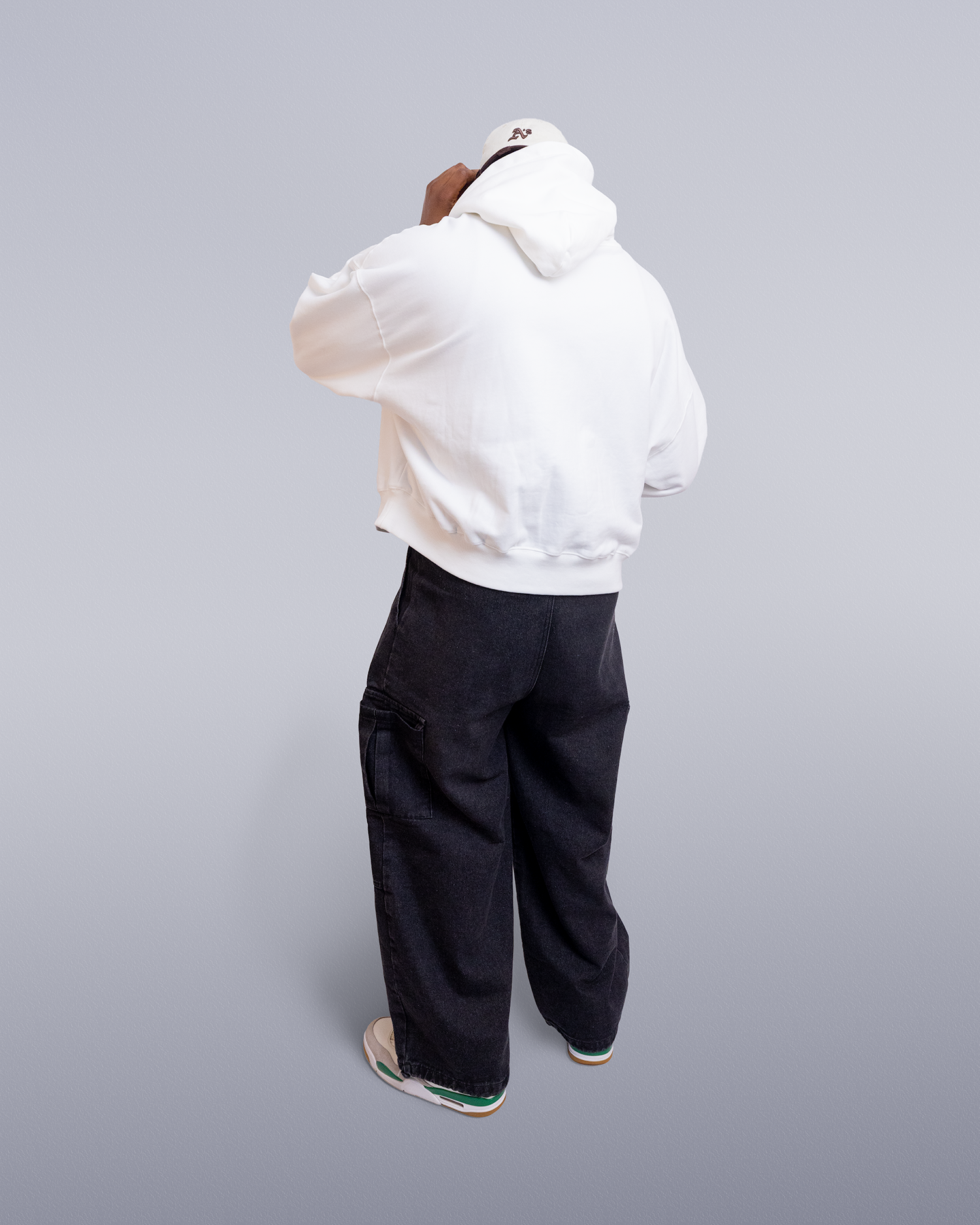Person wearing a white hoodie and black pants on a gray background option1_essential