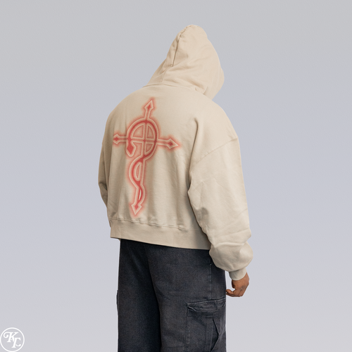 A person shown from the back wearing a cream-colored cropped hoodie with a large red cross-and-snake graphic on the back, paired with dark gray cargo pants, against a light gray studio background. option1_beige