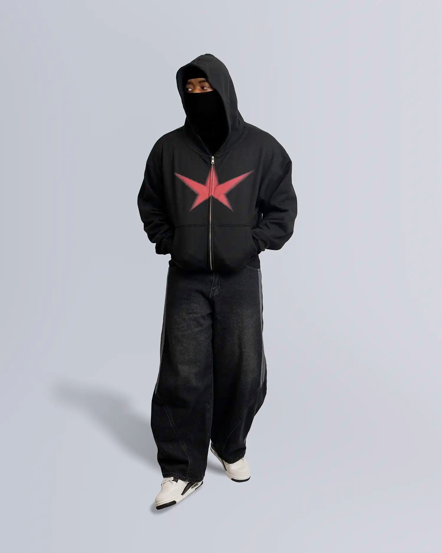 Model standing against light-gray backdrop wearing a black zip-up hoodie with red star design. option1_zip-up option2_black