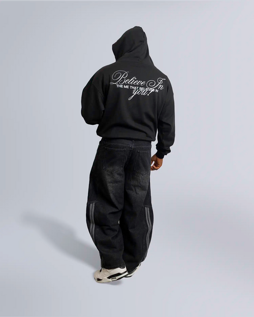 Model standing against light-gray backdrop wearing a black hoodie with words "Believe in the me that believes in you" on back option2_black