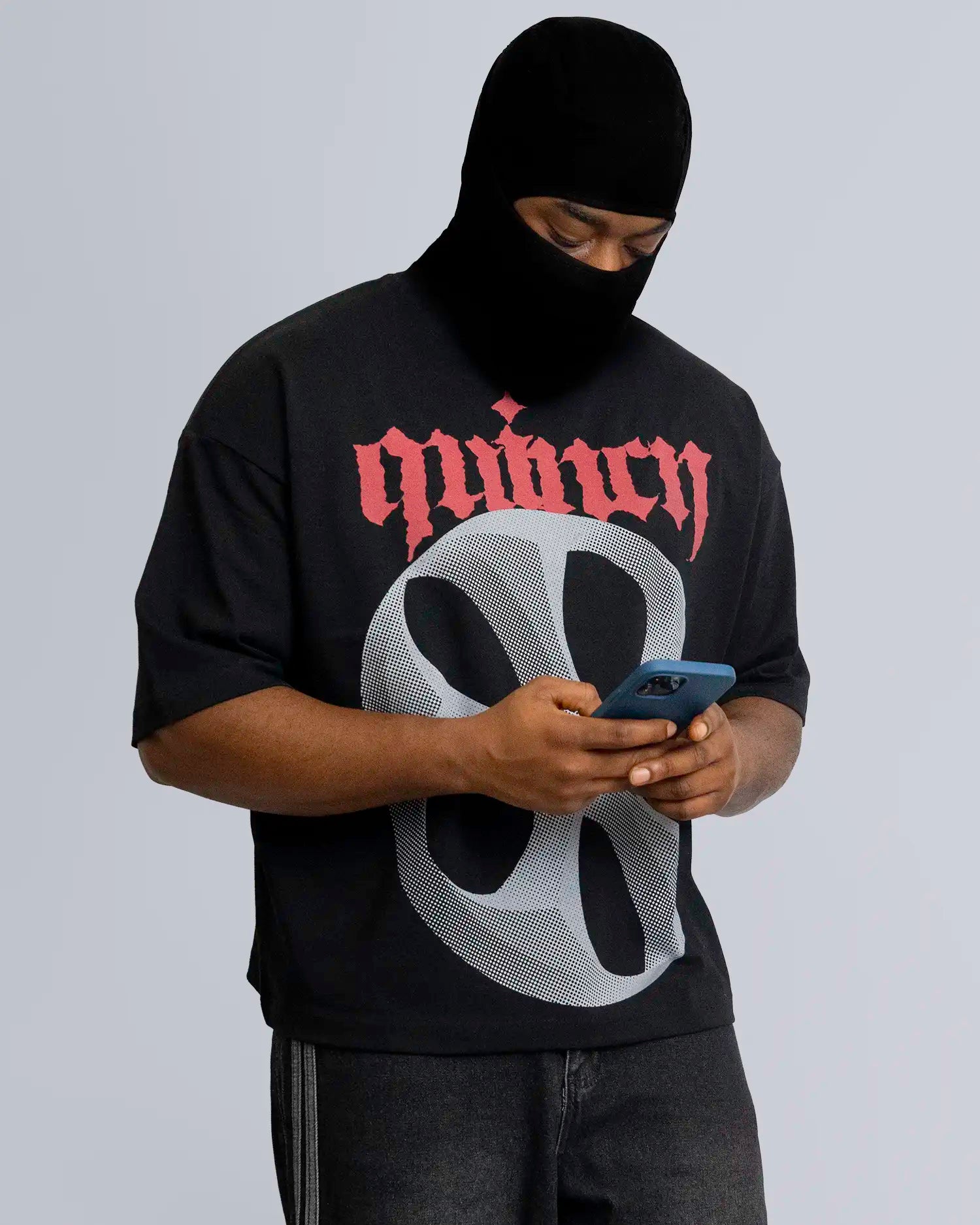 Person wearing a black hoodie with red and white design, using a phone on a gray background option1_black