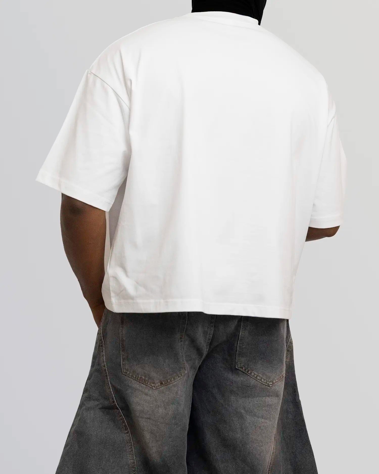 Person wearing a plain white t-shirt and dark pants on a light gray background option1_white