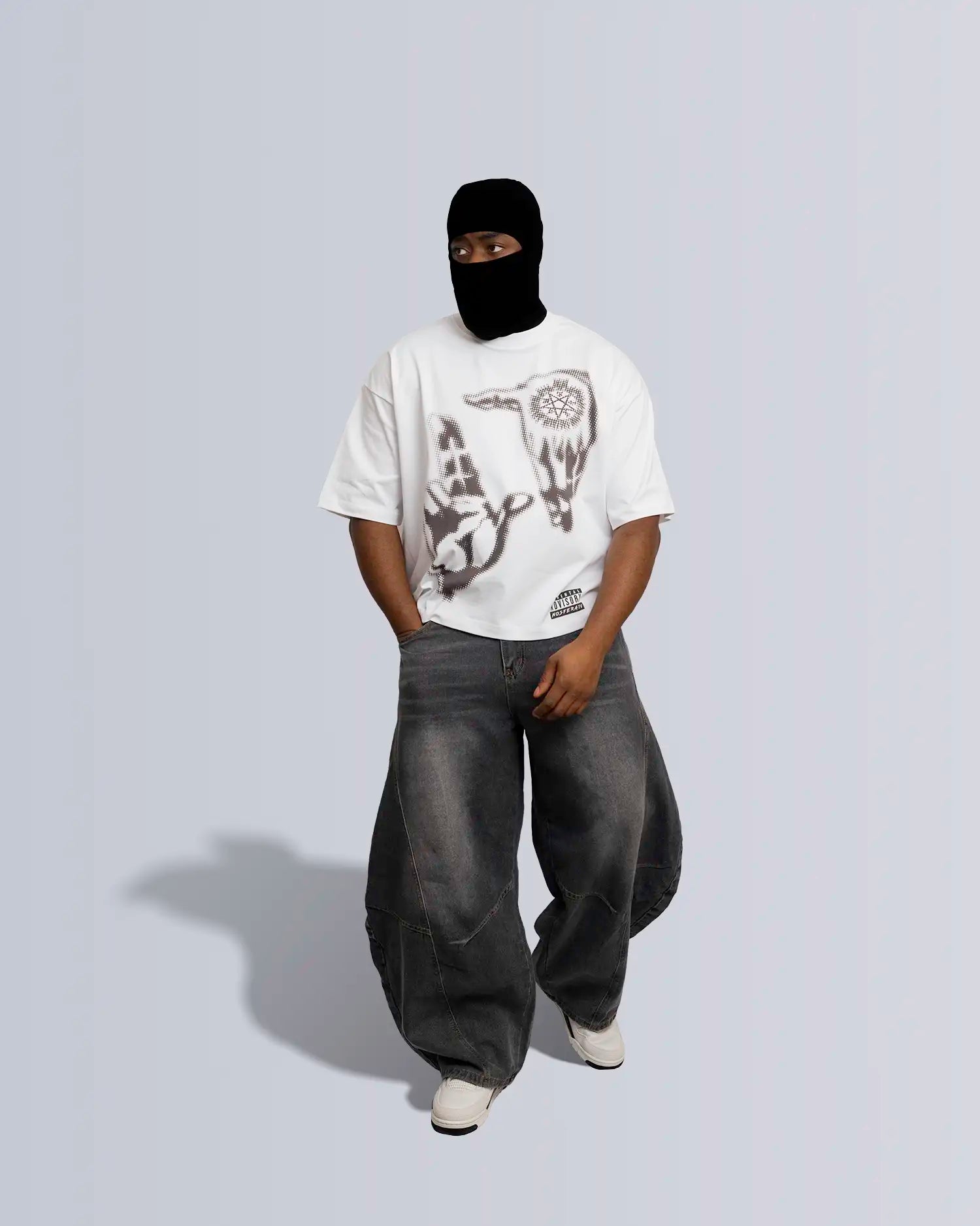 Person wearing a white t-shirt with graphic design and dark pants on a light gray background