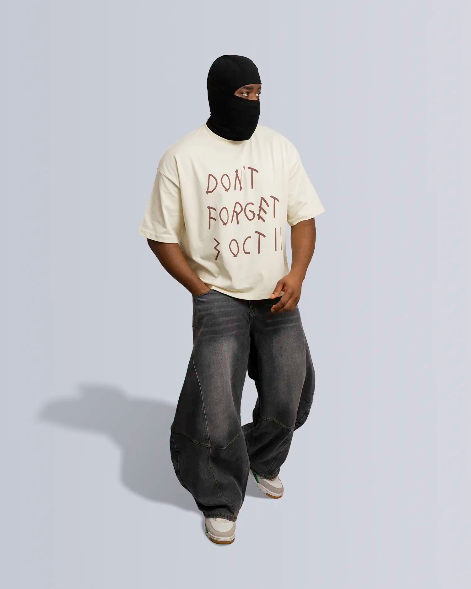Person wearing a beige t-shirt with text and dark pants on a light gray background option1_beige