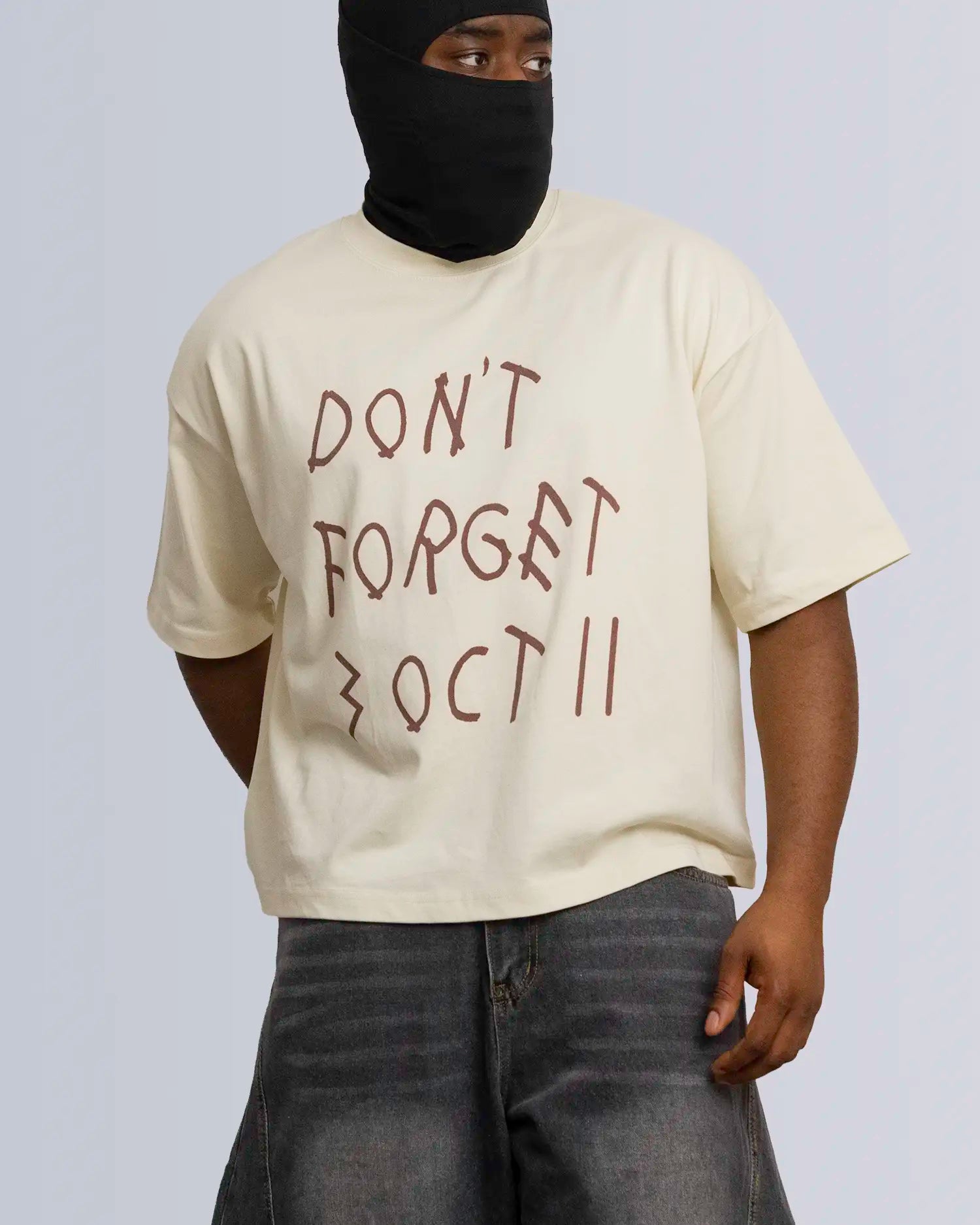 Person wearing a beige t-shirt with 'DON'T FORGET 3 OCT 11' text and a black balaclava on a plain background option1_beige